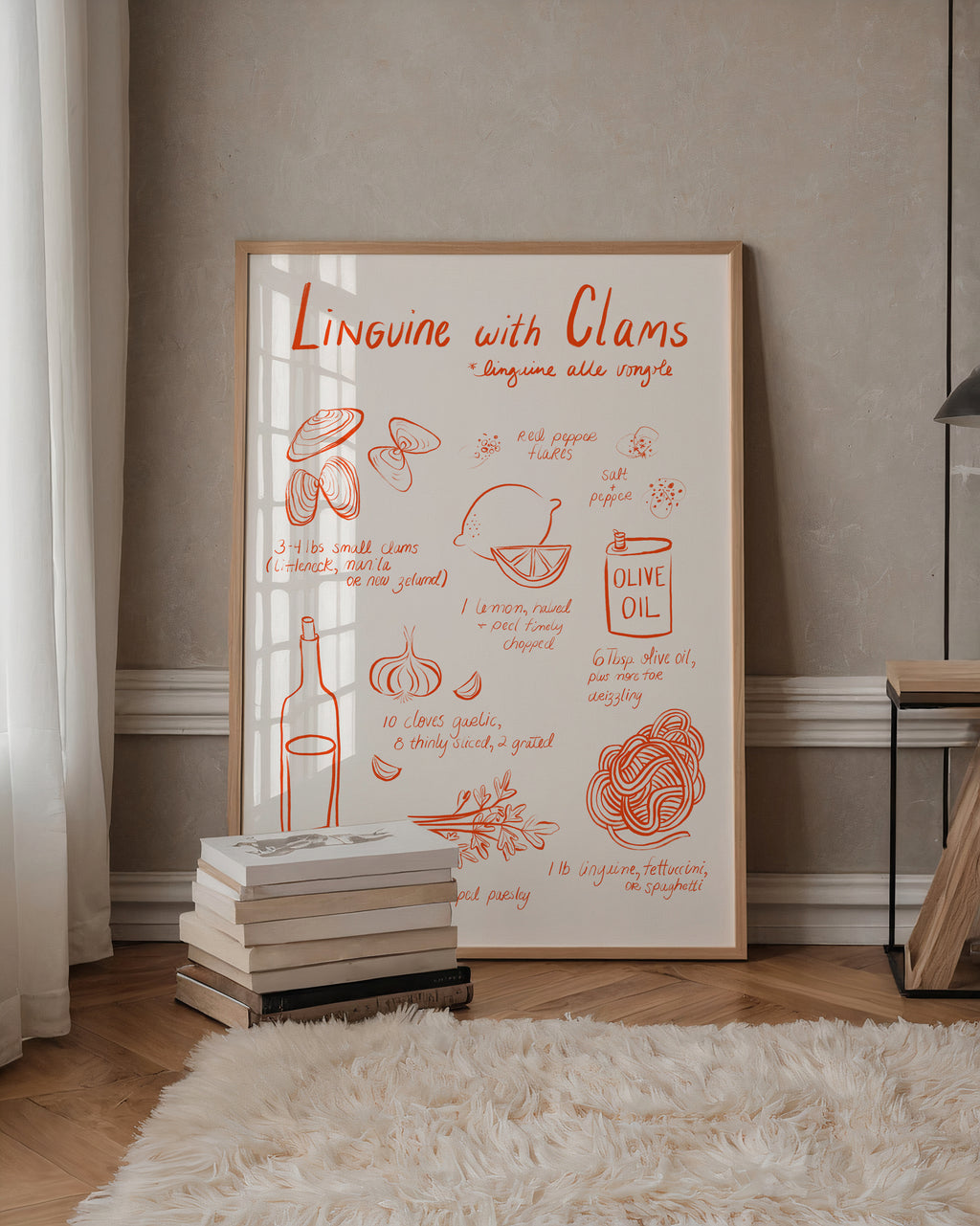 A framed Italian recipe-style art print titled "Linguine with Clams" leans against a beige wall in a styled room with wood flooring, a white rug, books, and a side table.