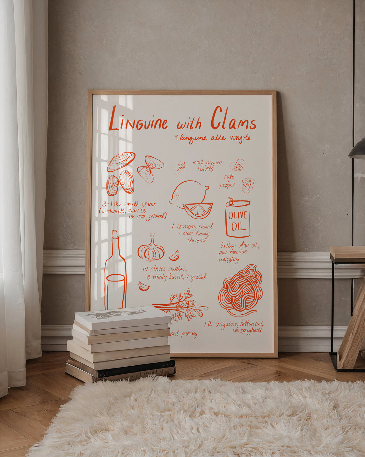 A framed Italian recipe-style art print titled "Linguine with Clams" leans against a beige wall in a styled room with wood flooring, a white rug, books, and a side table.
